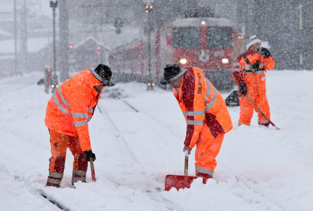 Радници чисте шине на жељезничкој станици у Дисентис у Швајцарској. Јак снијег у југоисточној Швајцарској изазвао је проблеме у железничком саобраћају.