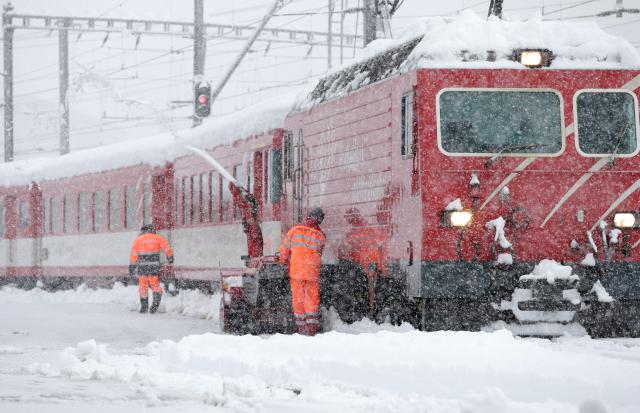 Радници чисте шине на жељезничкој станици у Дисентис у Швајцарској. Јак снег у југоисточној Швајцарској изазвао је проблеме у железничком саобраћају.